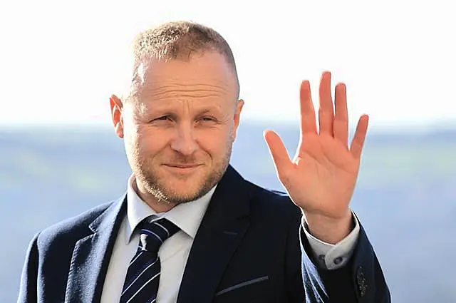 A close-up of Jamie Bryson waving