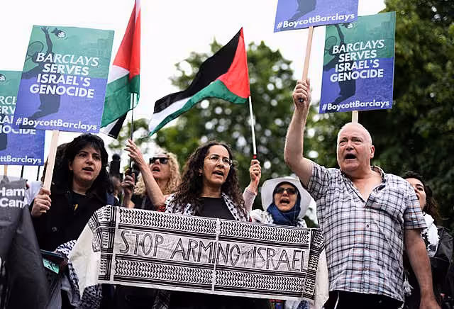 A group of protesters holding signs and Palestinian flags