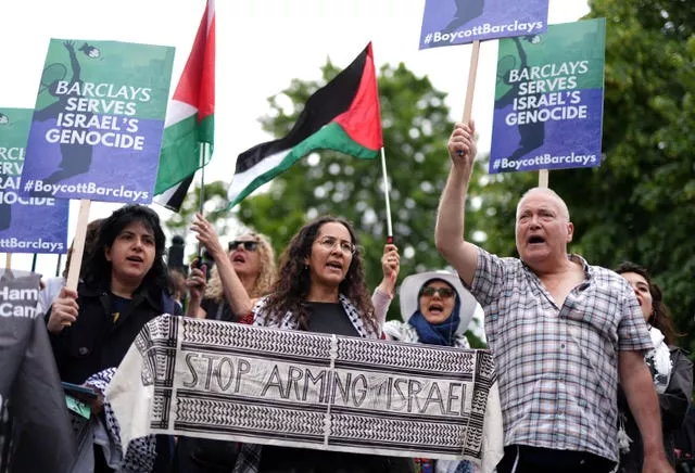 A group of protesters holding signs and Palestinian flags