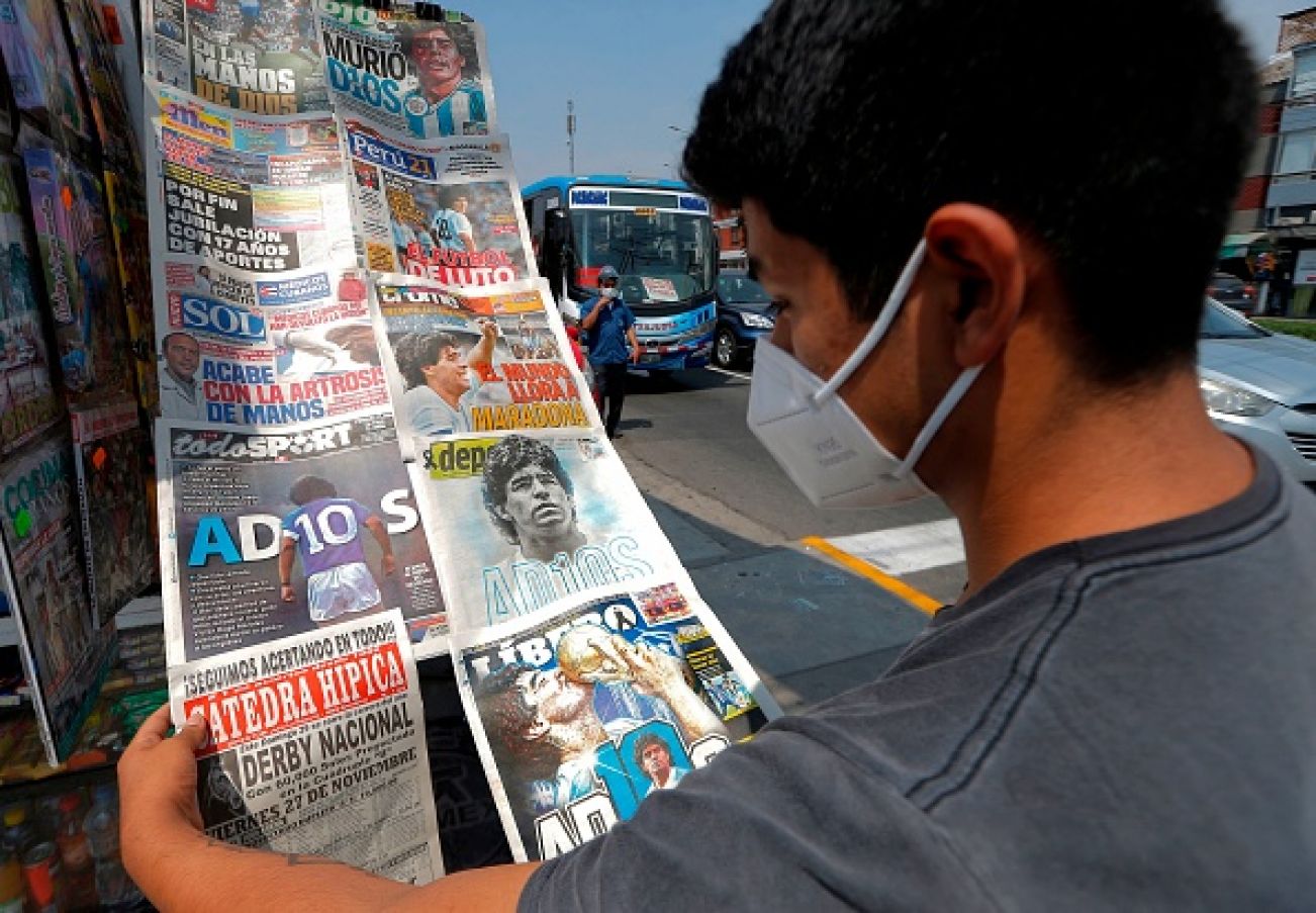 A Youngster Looks At Front Pages Of Newspapers Displayed In A Stand With The News Of Maradona's Death. Photo: Luka Gonzalez/Afp Via Getty Images