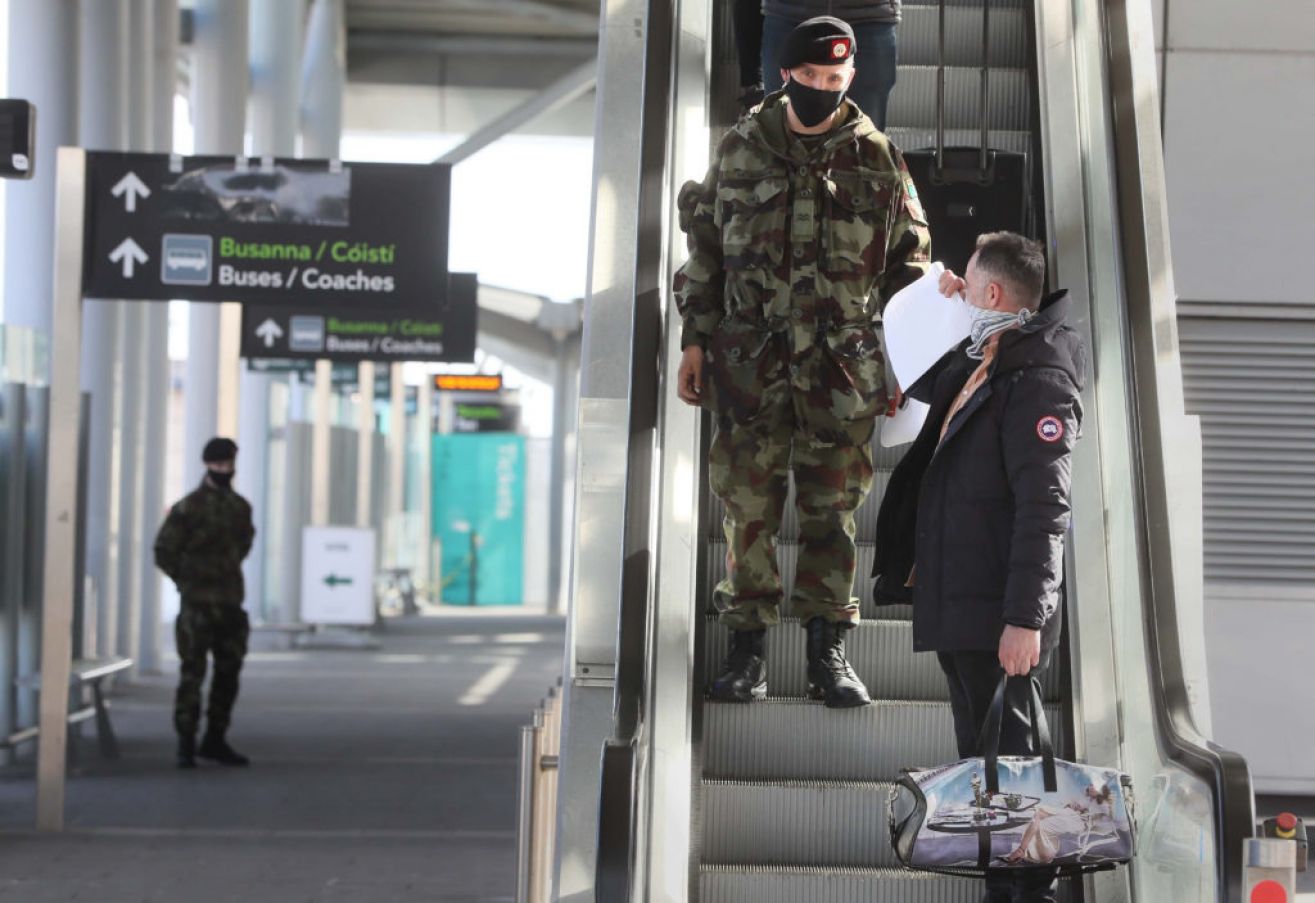 A Passenger Is Escorted To A Coach By A Member Of The Defence Forces After Arriving At Dublin Airport. Photo: Pa Images.