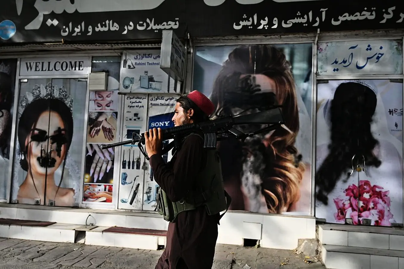 A Taliban Fighter Walks Past A Beauty Salon With Images Of Women Defaced Using Spray Paint In In Kabul. Photo: Wakil Kohsar/Afp Via Getty Images