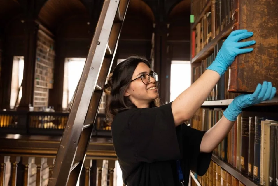 Project assistant Tünde Kutle removes books from the old Library collections for cleaning 