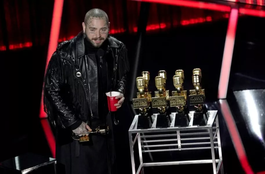 Post Malone took home nine awards on the night, including the biggest prize, top artist. He proudly posed with his golden trophies (AP Photo/Chris Pizzello)