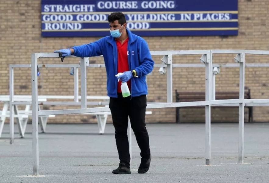 A course worker disinfects hand rails at The Curragh Racecourse, Co Kildare. Photo: Brian Lawless/PA