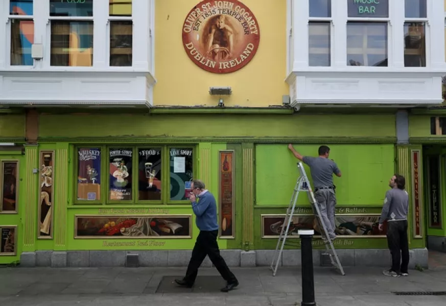 Workers board up the windows of Oliver St John Gogarty’s pub in Dublin’s Temple Bar. Photo: Brian Lawless/PA