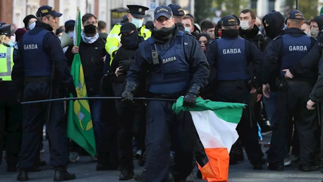 A member of the Garda Public Order Unit removes an Irish tricolour from counter demonstrators during an anti-lockdown protest outside Leinster House. Photo: Brian Lawless/PA Images.