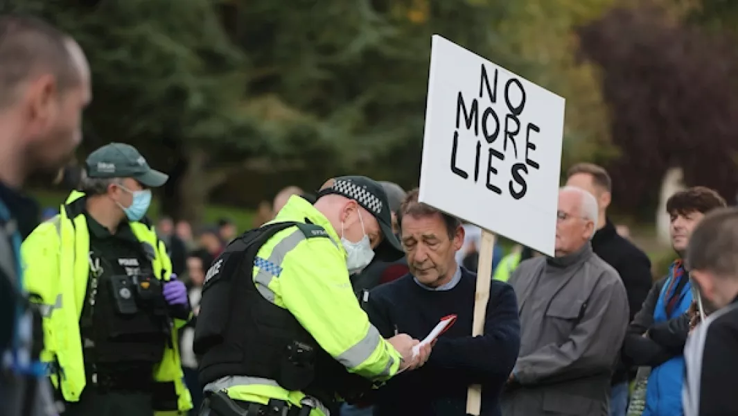 A police officer hands out an on the spot fine to a protester on the Stormont estate in Belfast. Photo: Niall Carson/PA Images.