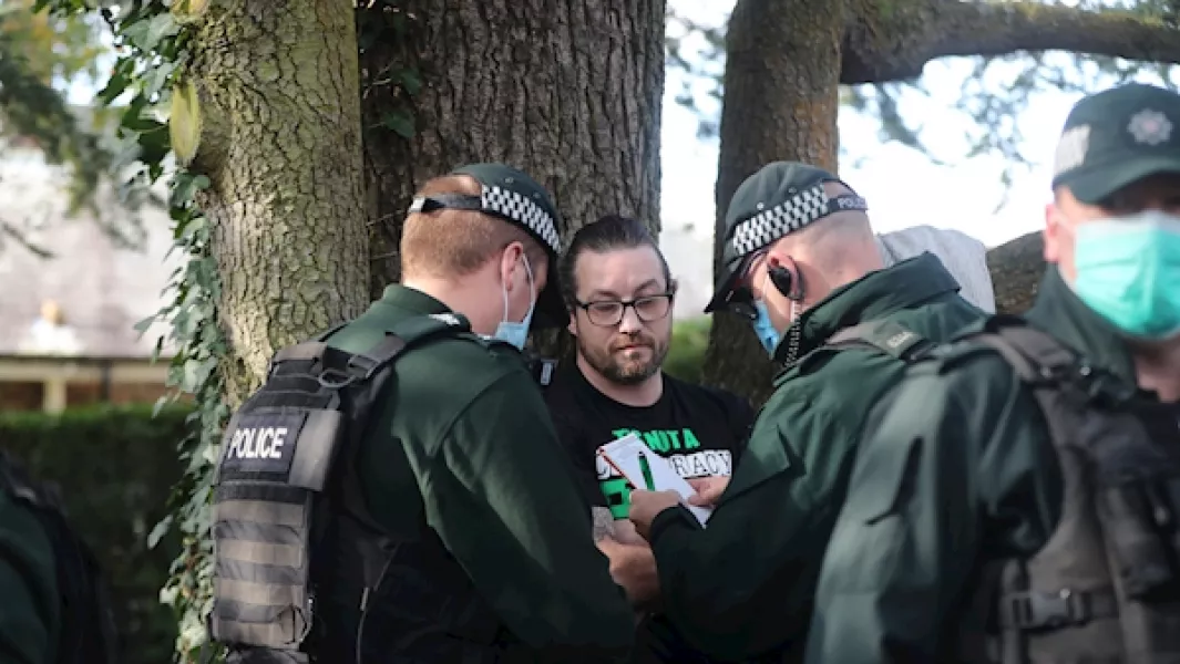 A police officer hands out an on the spot fine to a protester on the Stormont estate in Belfast. Photo: Niall Carson/PA Images.
