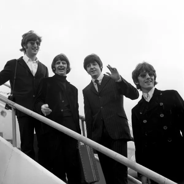 The Beatles board a plane in London in 1966 (PA)