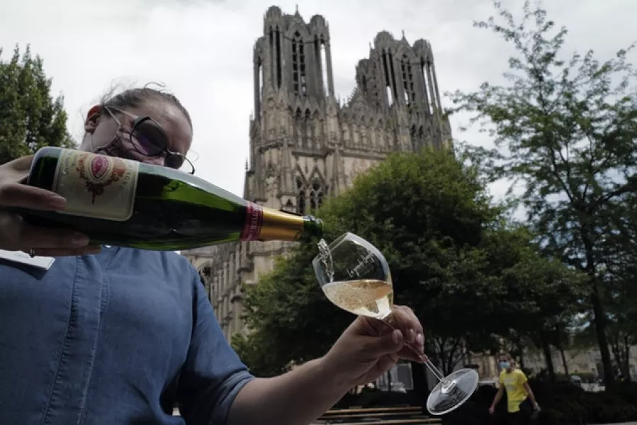A waitress serves a glass of champagne at La Grande Georgette restaurant in front of the cathedral in Reims, in the Champagne region (Francois Mori/AP)