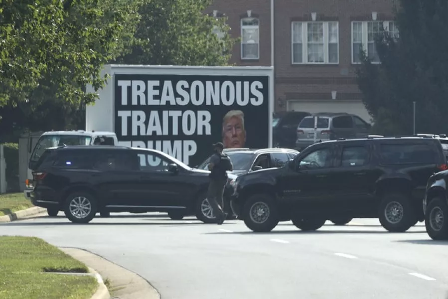 The motorcade for President Donald Trump passes a billboard truck as it turns into Trump National Golf Club in Sterling (AP)