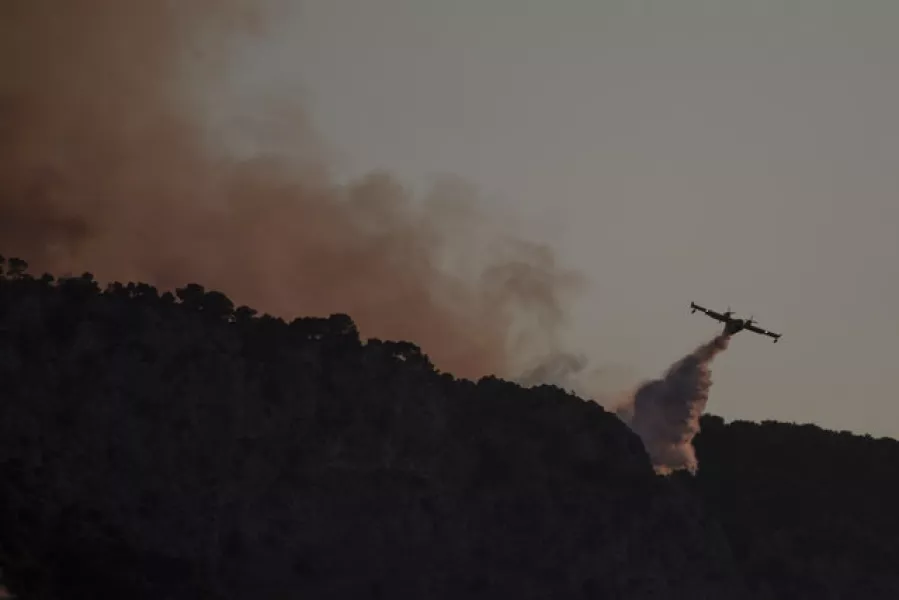 A firefighting airplane drops water in a hill near the area of Kehries, 50 miles south-west of Athens, on Thursday (Petros Giannakouris/AP)
