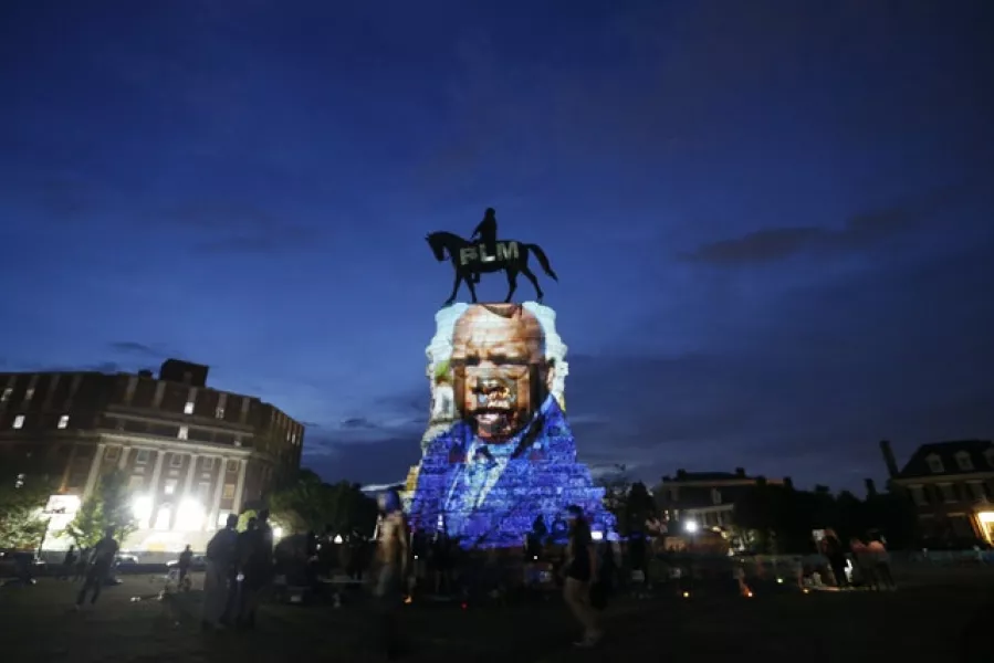 An image of the late Georgia Congressman and civil rights pioneer John Lewis is projected on to the pedestal of the statue of confederate General Robert E. Lee on Monument Avenue (Steve Helber/AP)