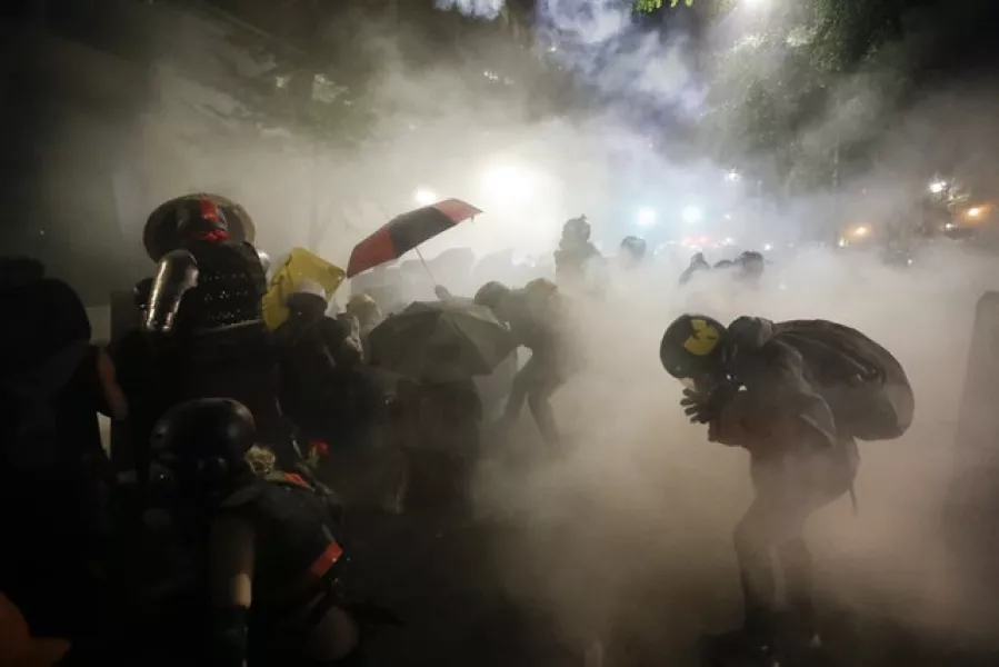 Federal officers launch tear gas at a group of demonstrators (Marcio Jose Sanchez/AP)