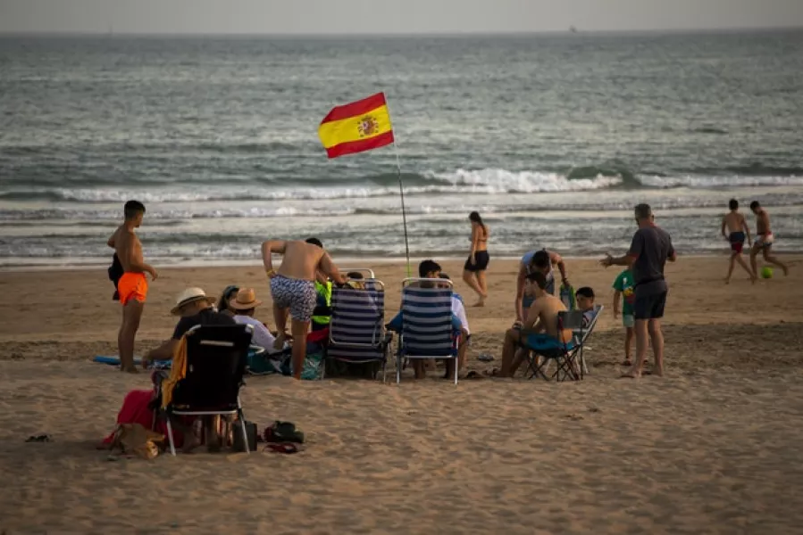 A Spanish flag waves as bathers enjoy the beach in Barbate, Cadiz province (Emilio Morenatti/AP)