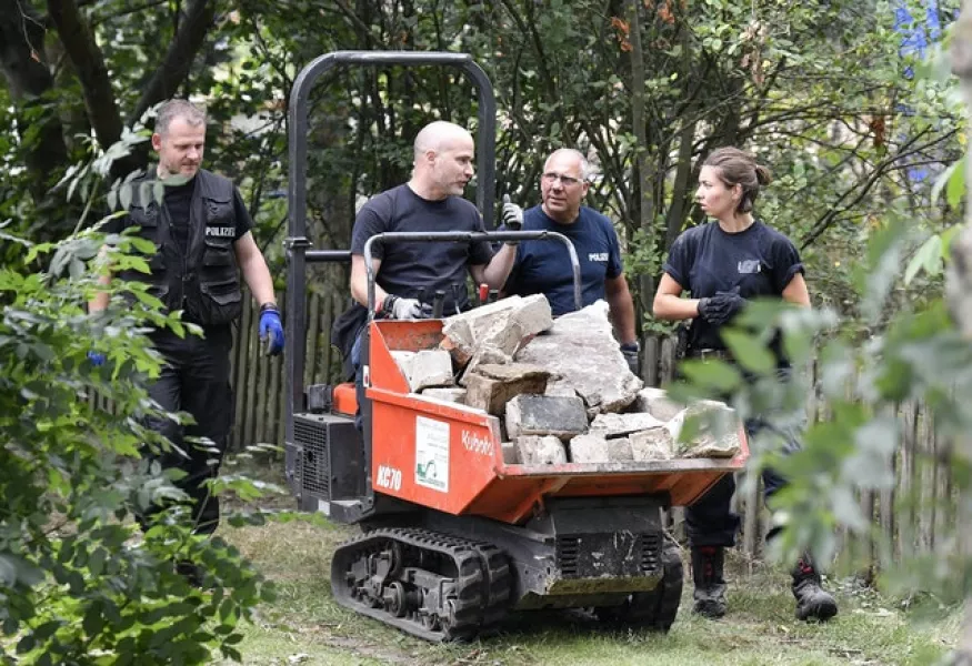 Officers use excavation equipment to sift the allotment (AP)