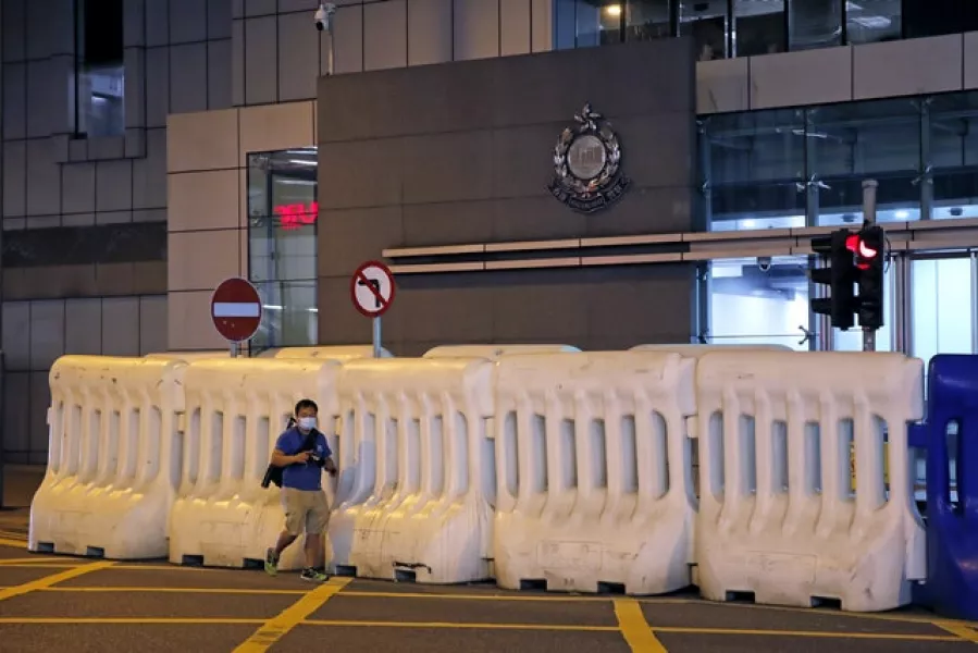 A journalist walks past the police headquarters in Hong Kong (Kin Cheung/AP)