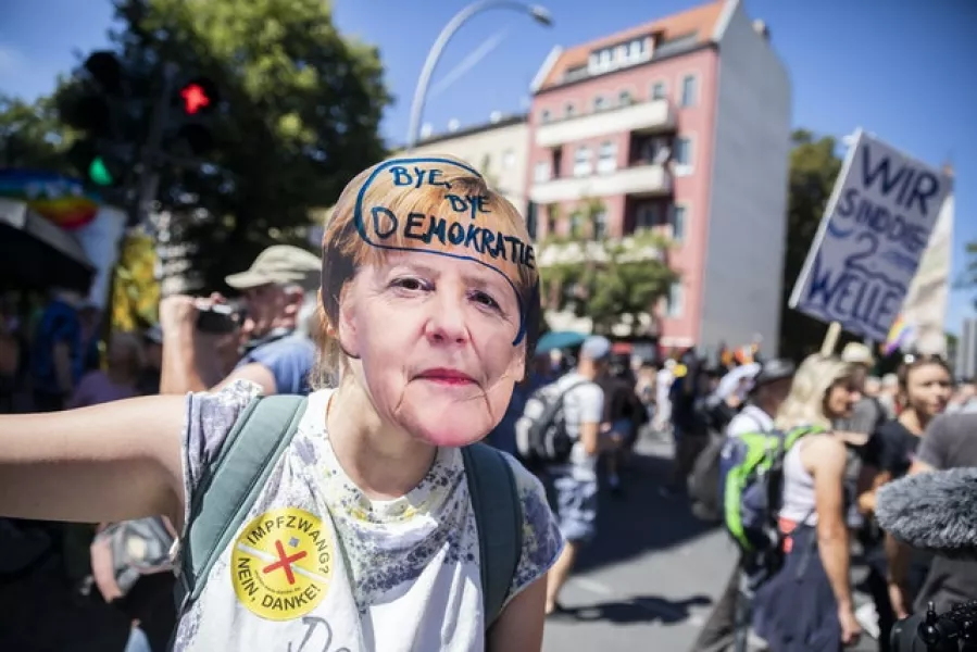 A woman wears a Angela Merkel mask with the inscription “Bye bye democracy”(Christoph Soeder/AP)