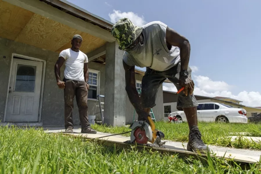 Darrel Duncombe stands nearby as Max Hall cuts a sheet of plywood to use to repair a roof in preparation for the arrival of Hurricane Isaias in Freeport, Grand Bahama, Bahamas (Tim Aylen/AP)