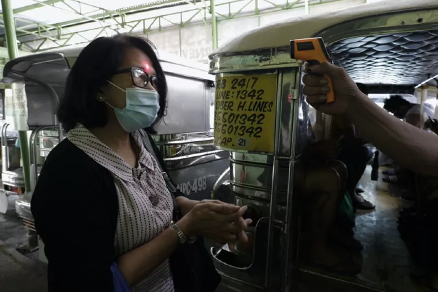 A woman’s temperature is measured in Quezon city, Philippines (Aaron Favila/AP)