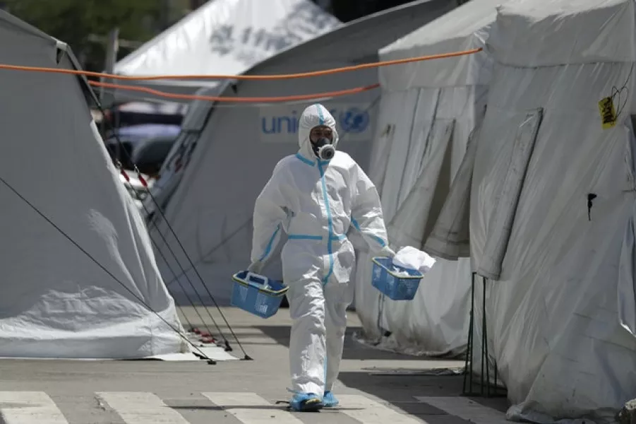 A health worker walks in between tents in a car park that has been converted into an extension of the Gat Andres Bonifacio Memorial Medical Centre in Manila (Aaron Favila/AP)