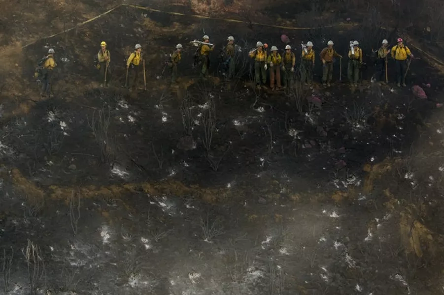 Hand crews line up to work on the remaining hot spots from the fire in Cherry Valley, California (Ringo H W Chiu/AP)