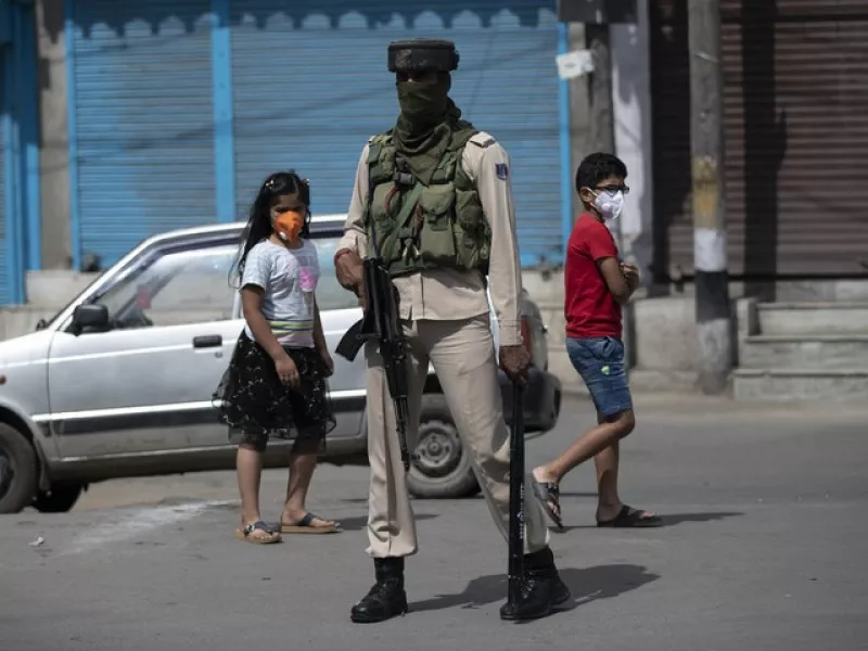 Kashmiri children walk past a paramilitary soldier (Mukhtar Khan/AP)