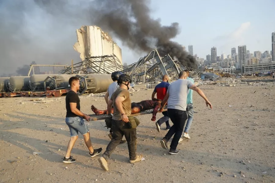 Civilians carry a victim at the explosion scene. Photo: Hussein Malla/AP