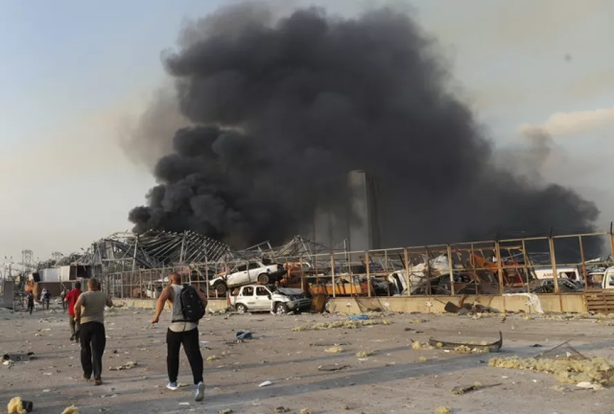 Port workers run to the scene of the explosion (Hussein Malla/AP)