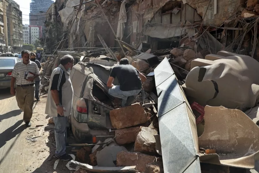 People inspect a damaged car (Bilal Hussein/AP)