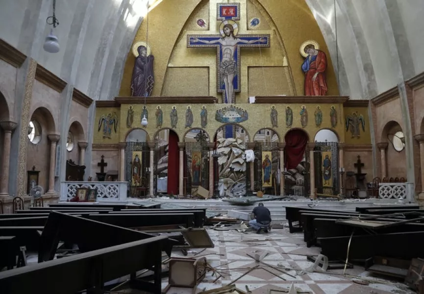 A man removes religious icons from the floor of a damaged church in Beirut (Hussein Malla/AP)