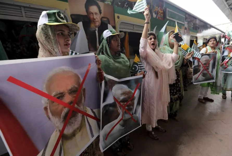 Women hold crossed out portraits of Indian prime minister Narendra Modi as they participate in a train march (Fareed Khan/AP)