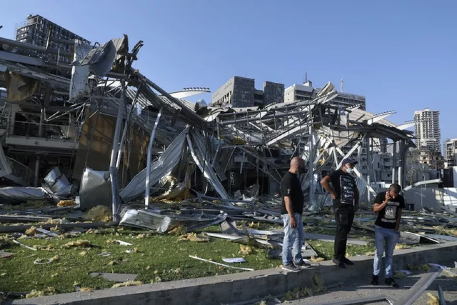 People stand in front of a destroyed building near the scene of the explosion (Bilal Hussein/AP)