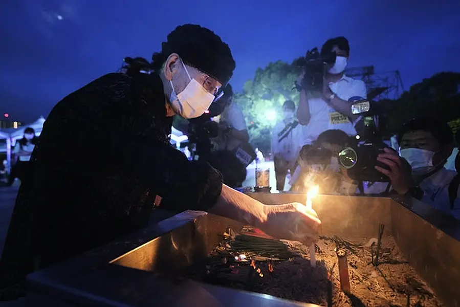 While a visitor lit a candle in front of the cenotaph for the atomic bombing victims before the start of the ceremony (AP Photo/Eugene Hoshiko)