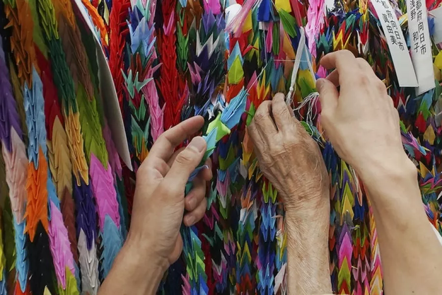 Hatsue Onda, centre, is helped by Kengo Onda to offer strings of paper cranes to the victims of the 1945 Atomic bombing near Hiroshima Peace Memorial Museum in Hiroshima (Eugene Hoshiko/AP)