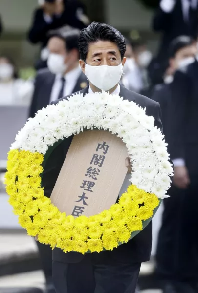 Japanese Prime Minister Shinzo Abe carries the wreath at Nagasaki commemorations (Kyodo News/AP)