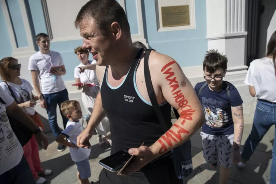 A man with writing on his arm that reads: ‘Tsikhanouskaya – Peace’, leaves the Belarusian Embassy after casting his vote (AP/Pavel Golovkin)