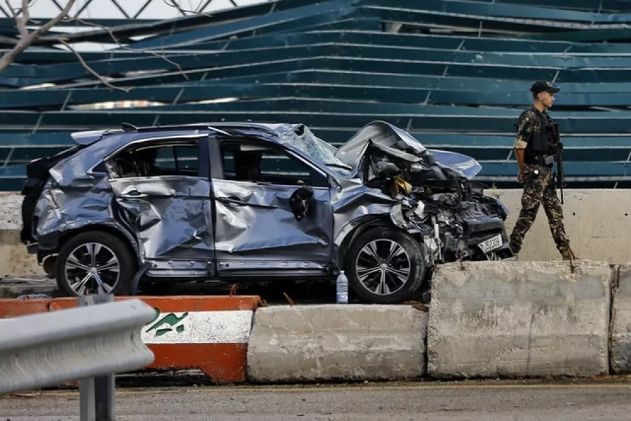 A soldier walks past a damaged car at the site of last week’s explosion (AP/Bilal Hussein)