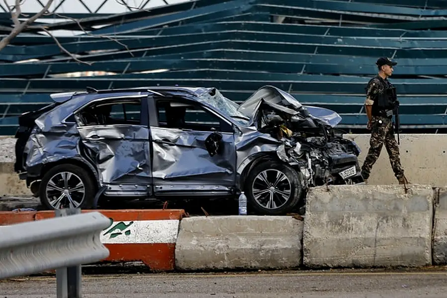 A soldier walks past a damaged car at the site of last week’s explosion (AP/Bilal Hussein)