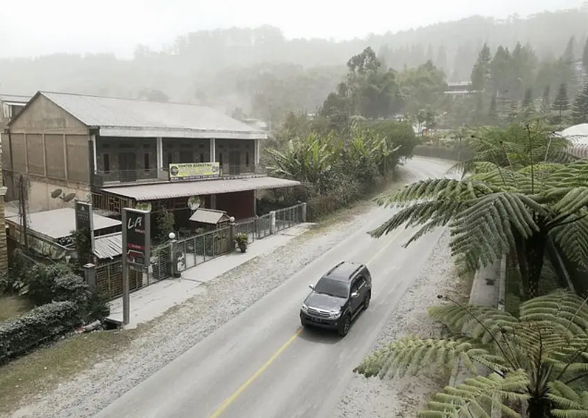 Volcanic ash covers the road nearby (AP)