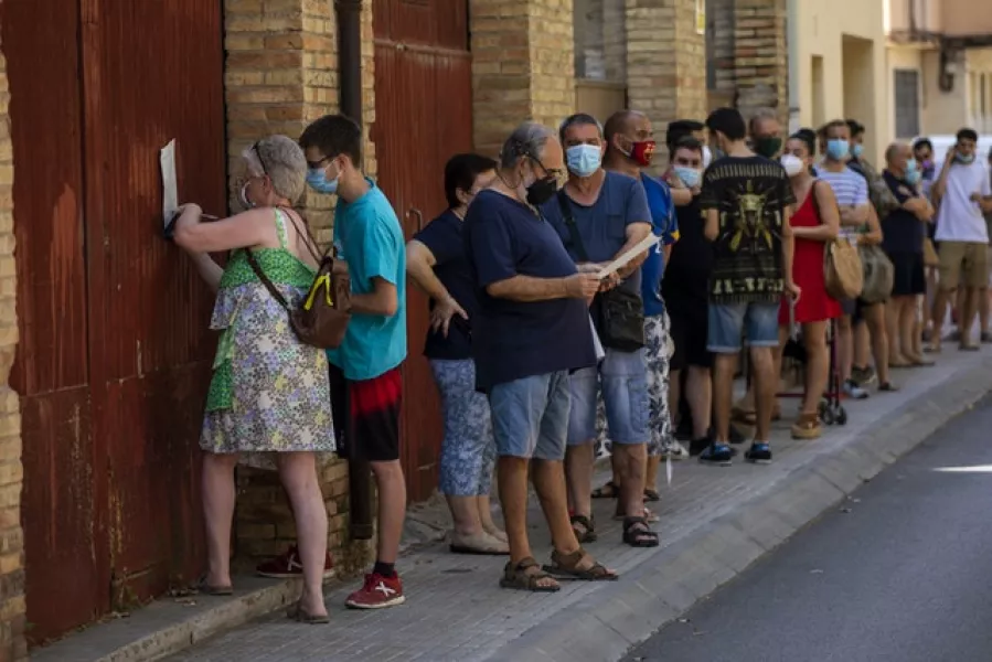 People wearing face masks queue up to be tested for Covid-19 in Barcelona (Emilio Morenatti/AP)