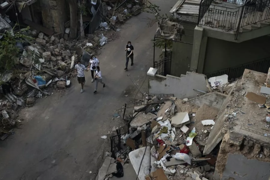People walk past debris from destroyed buildings in Beirut (Felipe Dana/AP)