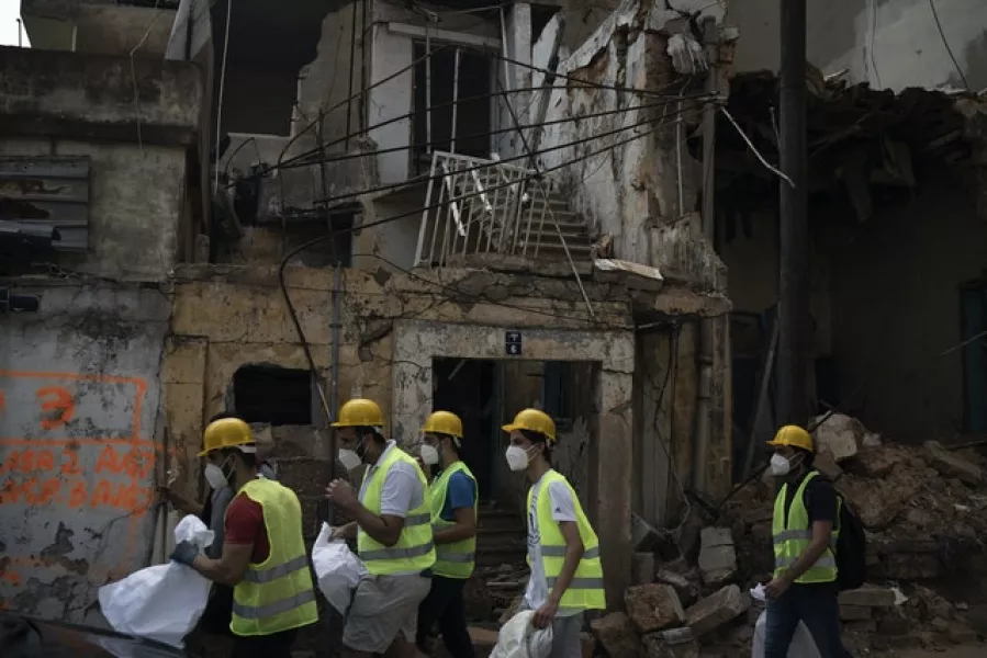 Volunteers from the American University of Beirut walk next to destroyed buildings (Felipe Dana/AP)