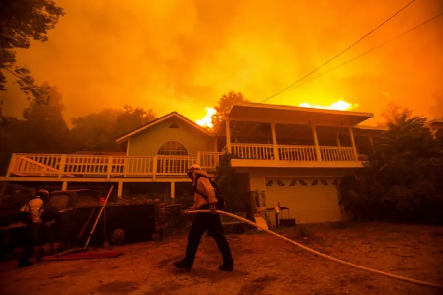 The fire burns behind a home (Ringo H.W. Chiu/AP)