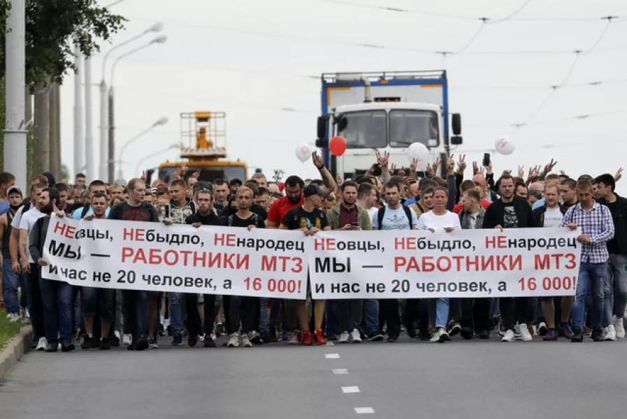 Workers hold a banner reading ‘we are not cattle, we are not sheep, we are workers of MTZ, we are not 20 people, we are 16,000’ (Sergei Grits/AP)