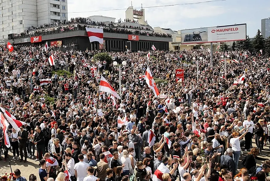 People hold old Belarusian National flags and gather at the place where Alexander Taraikovsky died (Dmitry Lovetsky/AP)