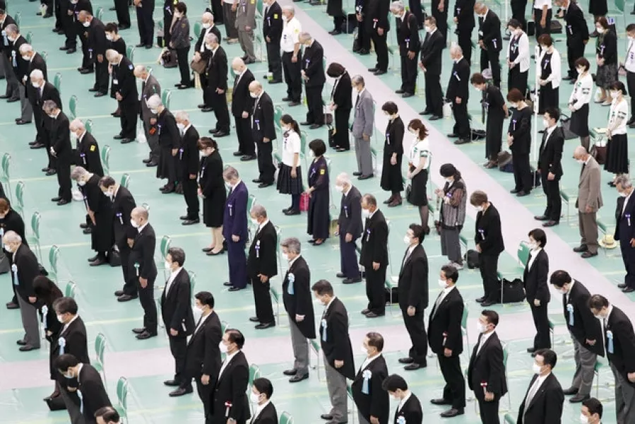 Attendees take a moment of silence during the memorial service in Tokyo. Photo: Kyodo News via AP
