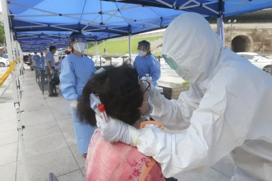 A health official takes samples from a woman during the Covid-19 testing at a makeshift clinic in Seoul (Ahn Young-joon/AP)