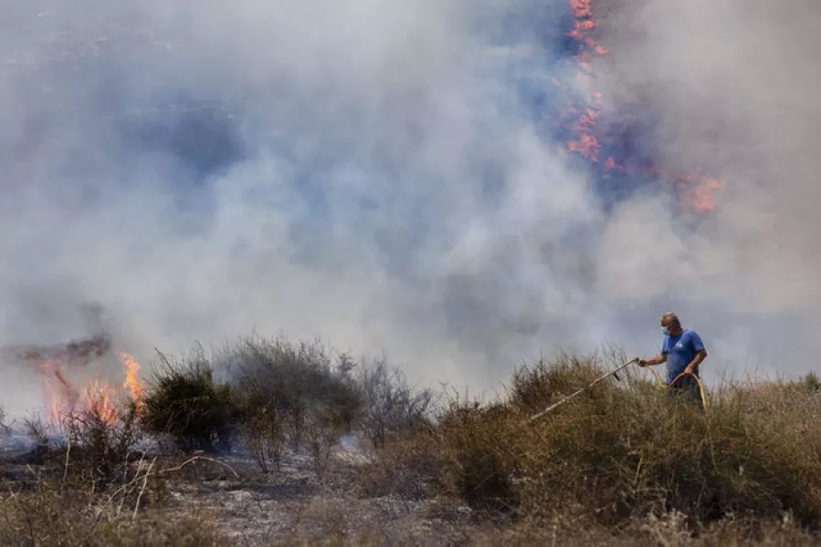 An Israeli worker from the Nature and Parks Authority attempts to extinguish a fire caused by a incendiary balloon launched by Palestinians from the Gaza Strip (Tsafrir Abayov/AP)